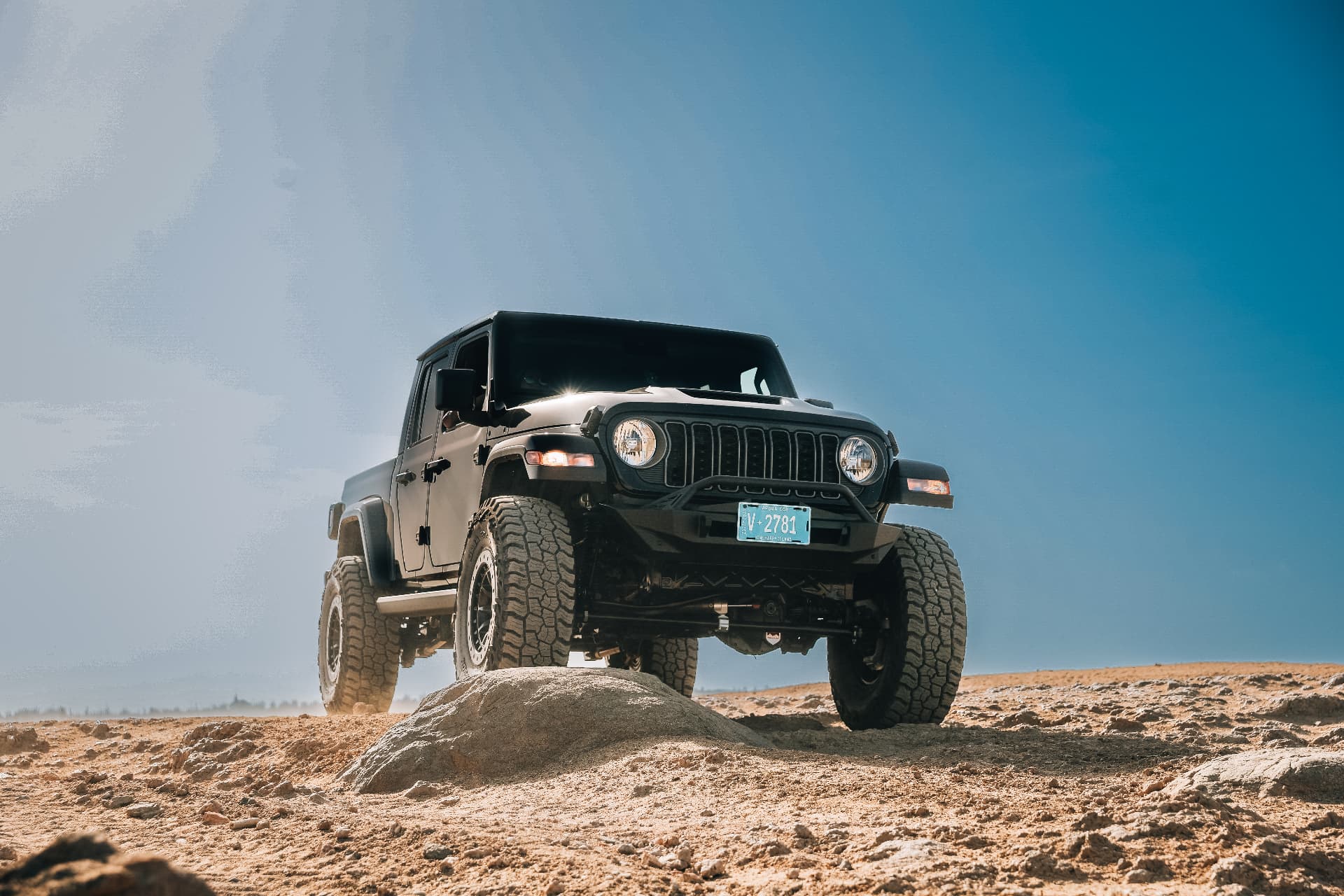 The Beast Jeep Gladiator climbing a rock on Aruba's desert terrain