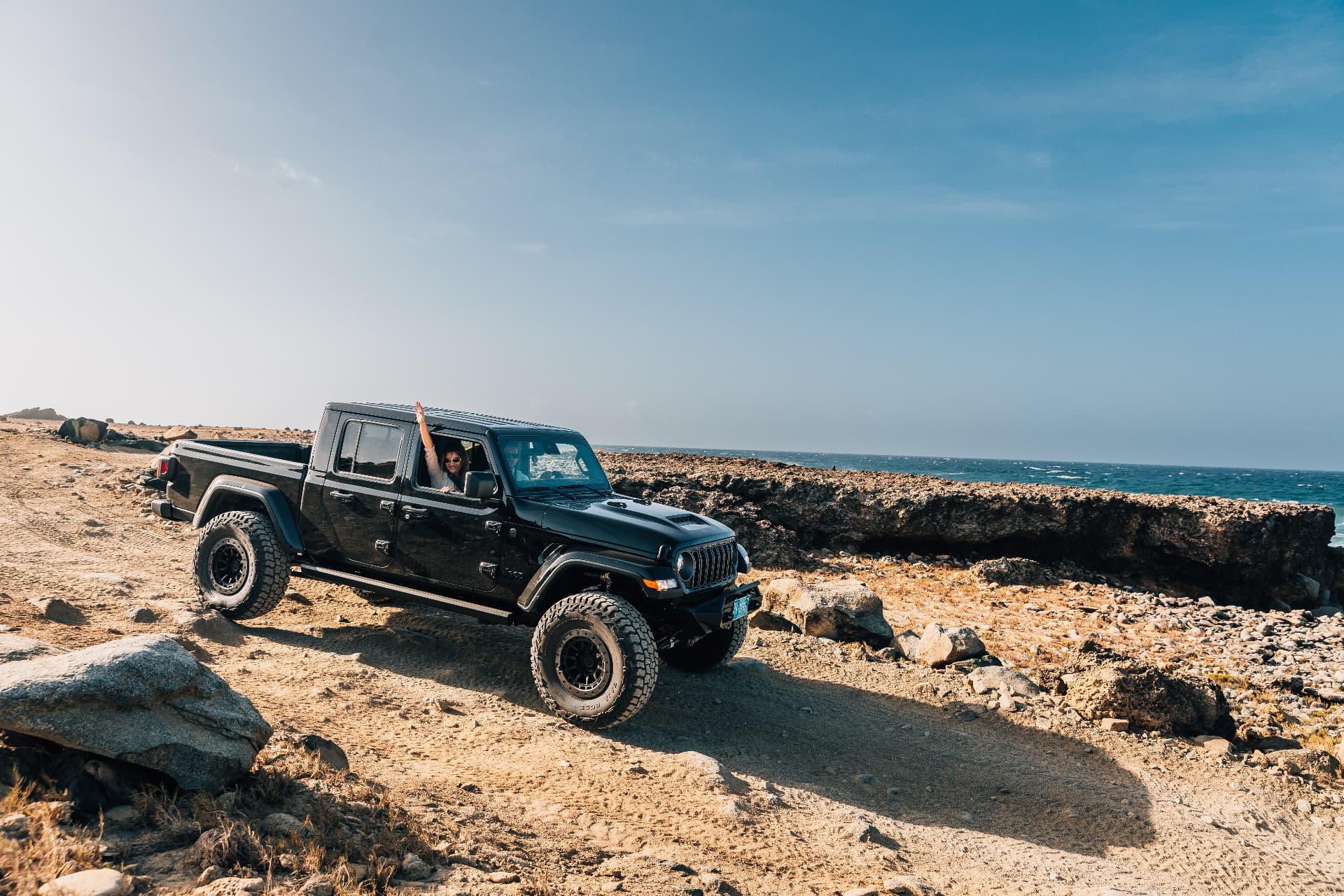 Aerial view of a 4×4 on a coastal dirt trail in Aruba at golden hour